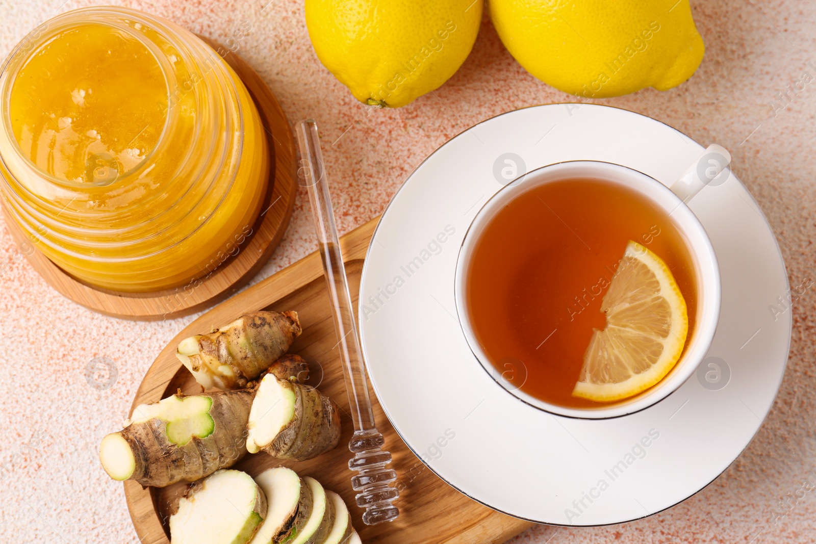 Photo of Tea, honey, lemon and ginger on beige textured table, flat lay
