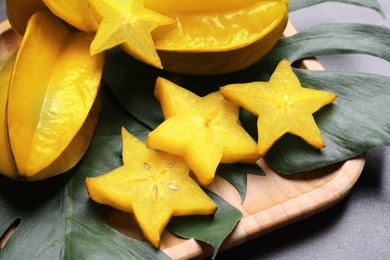 Delicious carambola fruits and slices on grey table