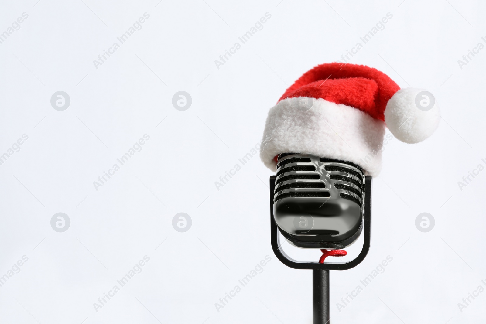 Photo of Retro microphone with Santa hat on white background, space for text. Christmas music