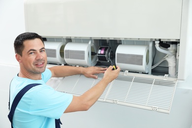 Photo of Technician repairing and checking air conditioner indoors