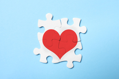 Image of Concept of love. White puzzle pieces with illustration of heart on light blue background, top view