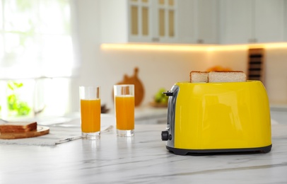Photo of Modern toaster with slices of bread and juice on white table in kitchen