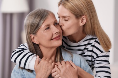 Daughter kissing her mature mother at home