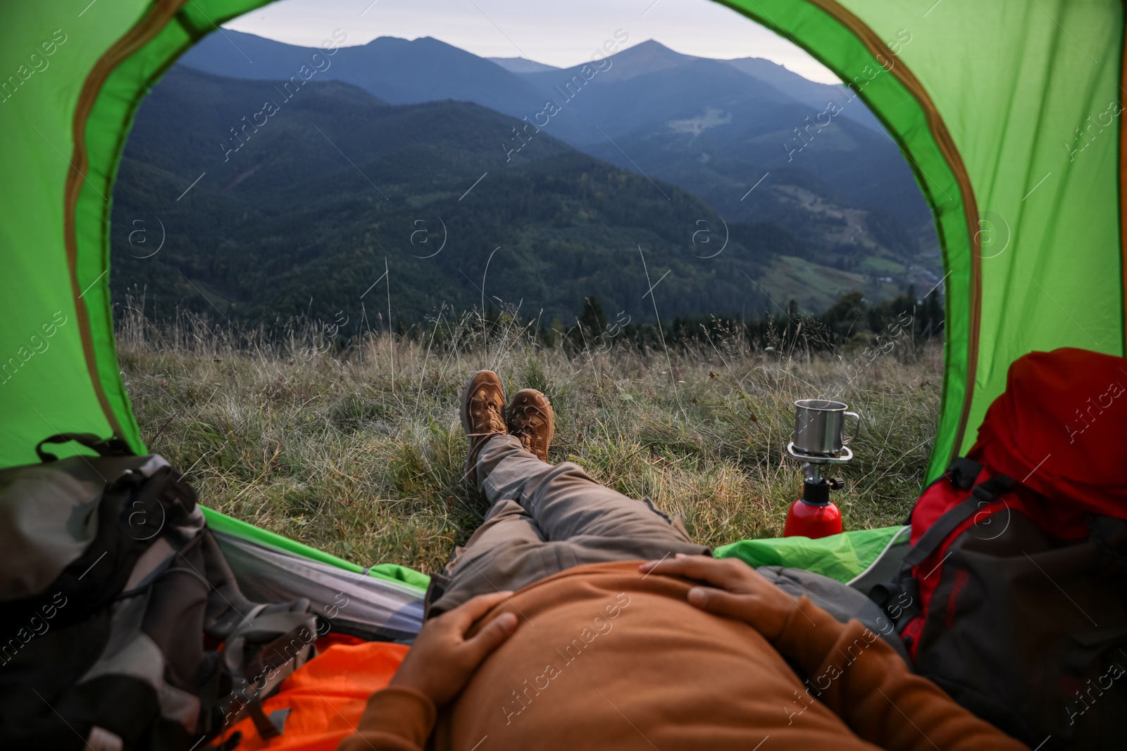 Photo of Man resting inside of camping tent in mountains, closeup