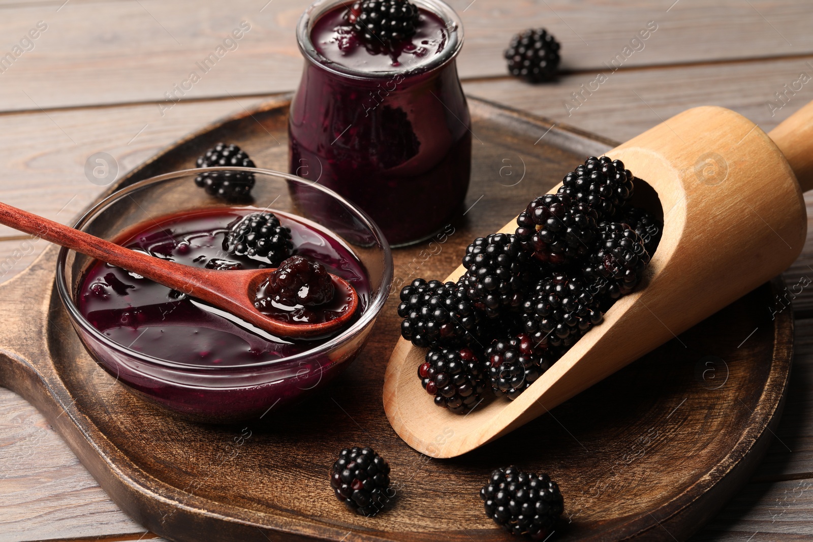 Photo of Tasty blackberry jam and fresh berries on wooden table, closeup