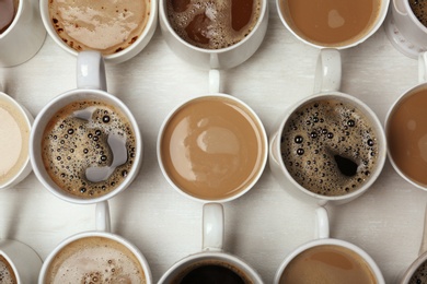 Many cups with tasty aromatic coffee on table, flat lay