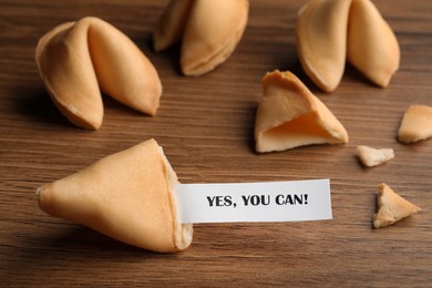 Image of Tasty fortune cookie with prediction Yes, you can! on wooden table, closeup