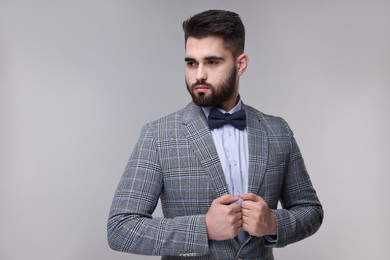 Photo of Portrait of handsome man in suit, shirt and bow tie on grey background. Space for text