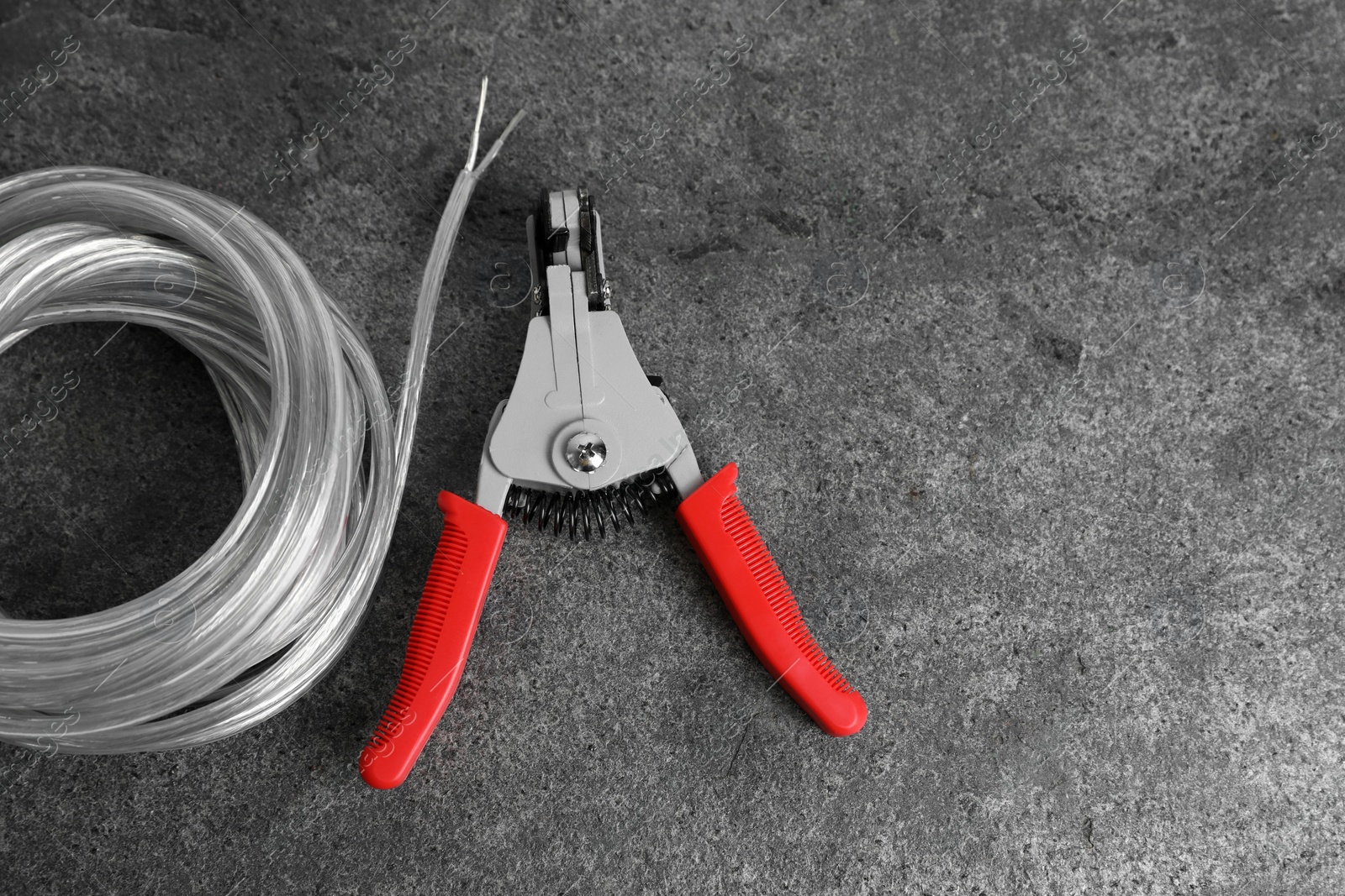 Photo of Cutters and cable with stripped wire on light gray textured table, flat lay. Space for text