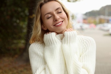 Photo of Happy woman in stylish warm sweater outdoors