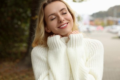 Happy woman in stylish warm sweater outdoors