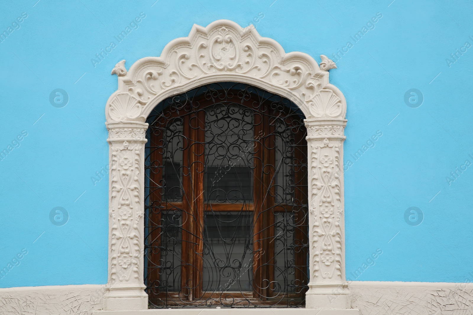 Photo of Light blue building with beautiful window and steel grilles