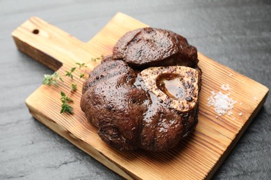 Piece of delicious grilled beef meat, thyme and salt on black table