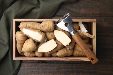 Photo of Tubers of turnip rooted chervil and peeler in crate on wooden table, top view