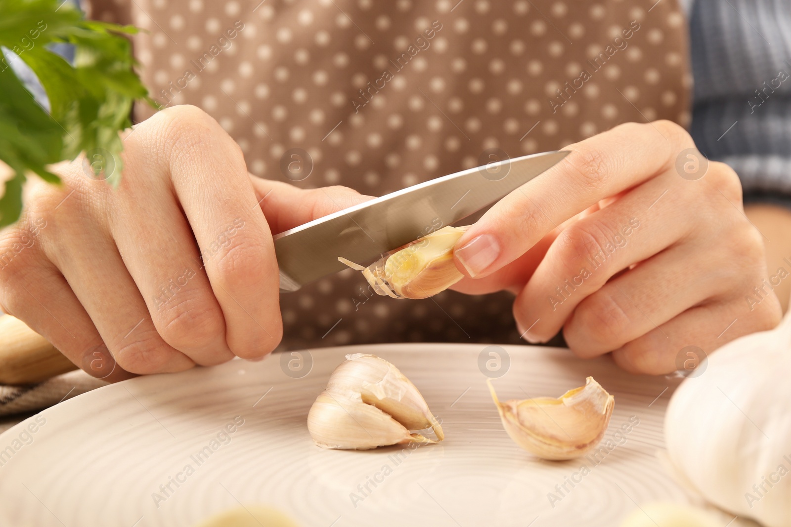 Photo of Woman peeling fresh garlic at table, closeup