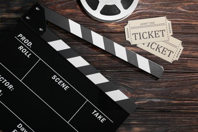 Photo of Clapperboard, movie tickets and film reel on wooden table, flat lay