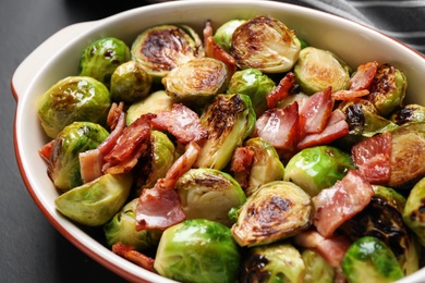 Photo of Delicious Brussels sprouts with bacon in baking pan, closeup