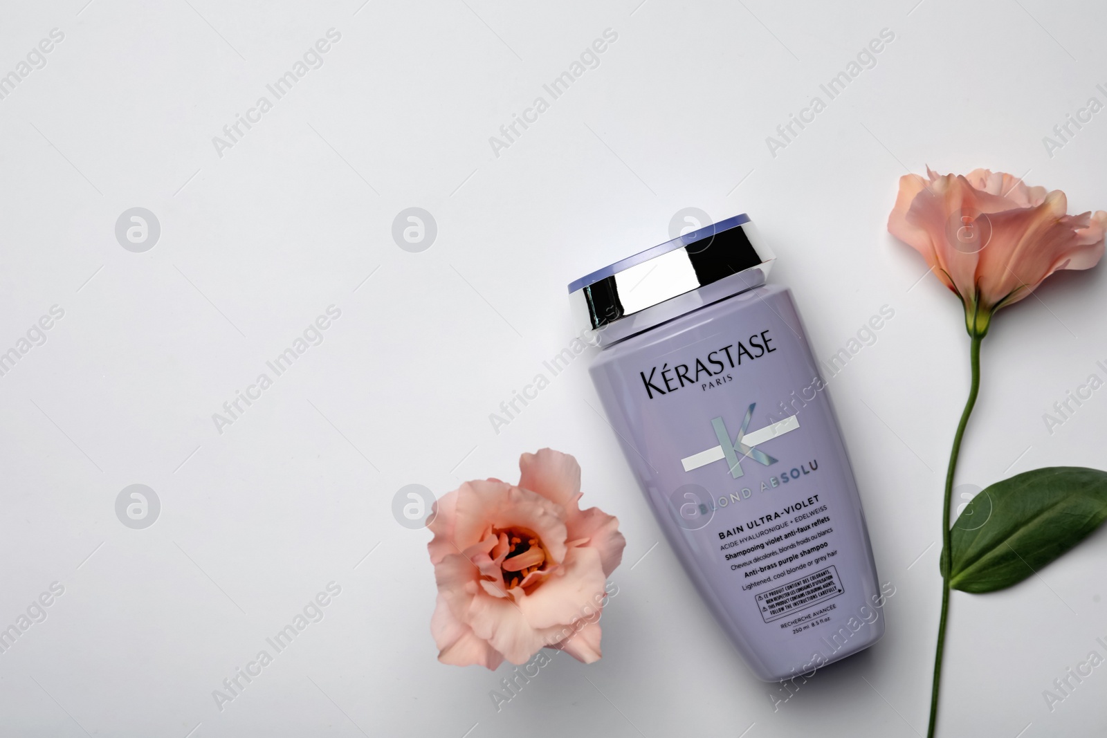 Photo of MYKOLAIV, UKRAINE - SEPTEMBER 07, 2021: Kerastase shampoo and beautiful flowers on light grey background, flat lay. Space for text