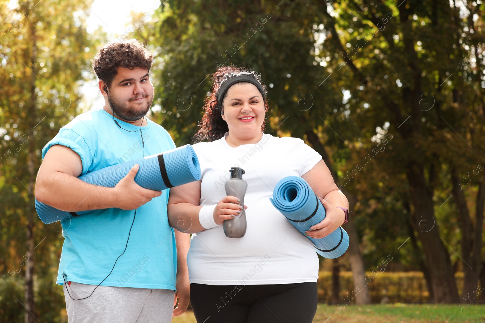 Photo of Overweight couple wearing sportswear with mats in park