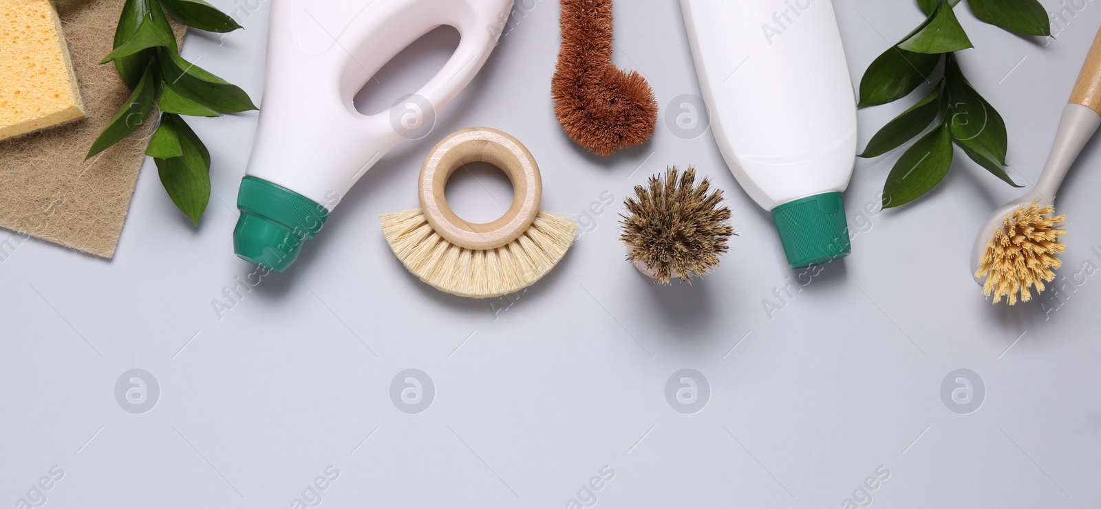 Photo of Flat lay composition with different cleaning supplies on light gray background, space for text