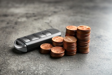 Car alarm key and coins on grey background