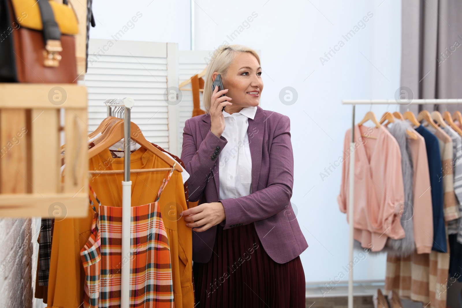 Photo of Female business owner talking on phone in boutique