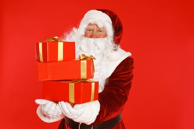 Authentic Santa Claus with gift boxes on red background