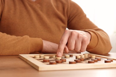 Photo of Man playing checkers at table in room, closeup