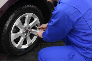 Photo of Mechanic checking tire air pressure at car service, closeup