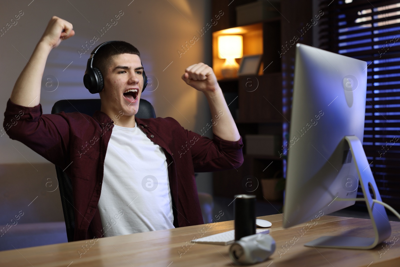 Photo of Emotional man playing video games on computer at table indoors