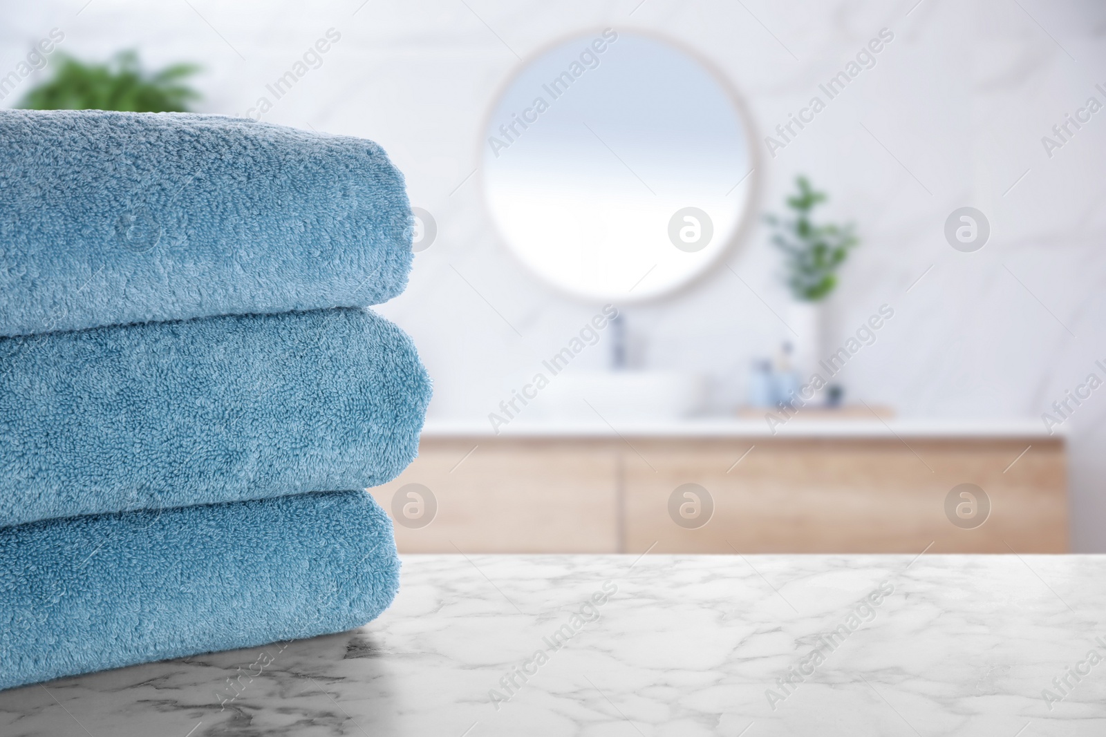 Image of Stack of fresh towels on marble table in bathroom. Space for text