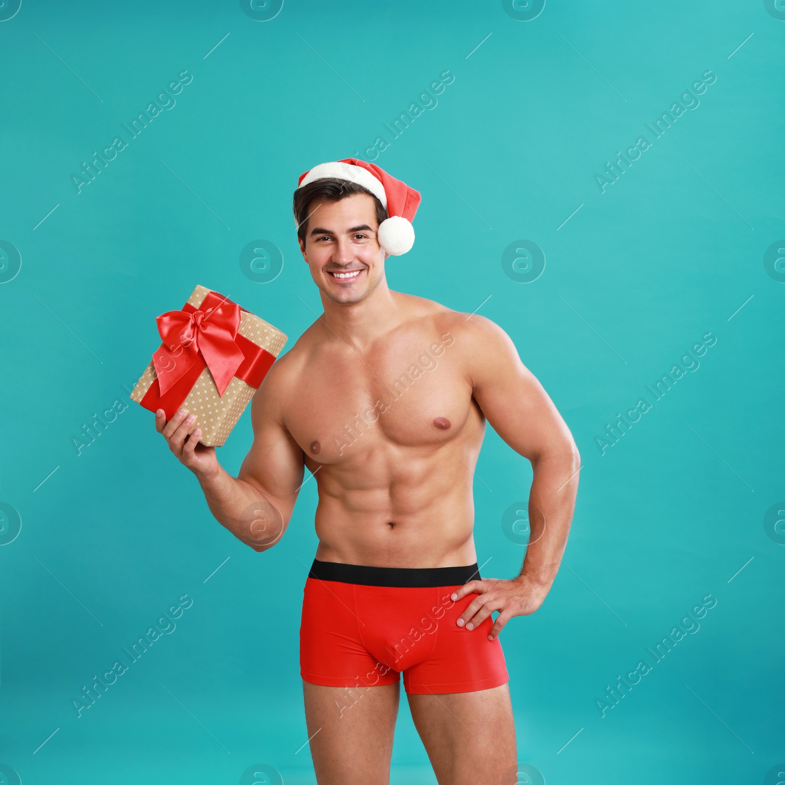 Photo of Sexy shirtless Santa Claus with gift on blue background