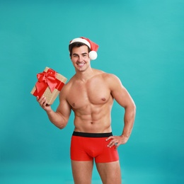 Photo of Sexy shirtless Santa Claus with gift on blue background