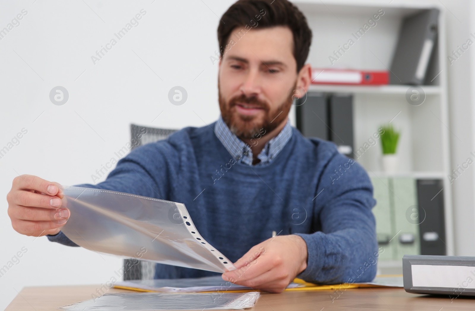 Photo of Businessman taking punched pocket on wooden table in office, selective focus