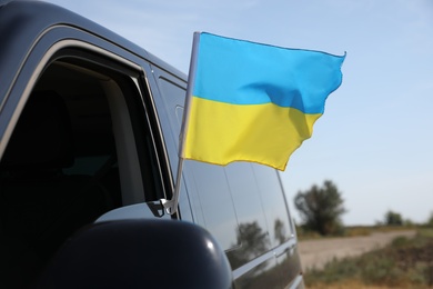 Photo of National flag of Ukraine on car window outdoors, closeup