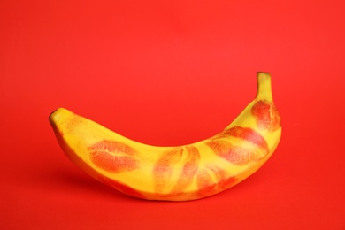 Photo of Fresh banana with lipstick marks on red background. Oral sex concept