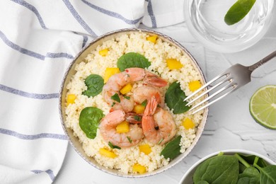 Photo of Tasty couscous with shrimps, bell pepper and basil served on white textured table, flat lay
