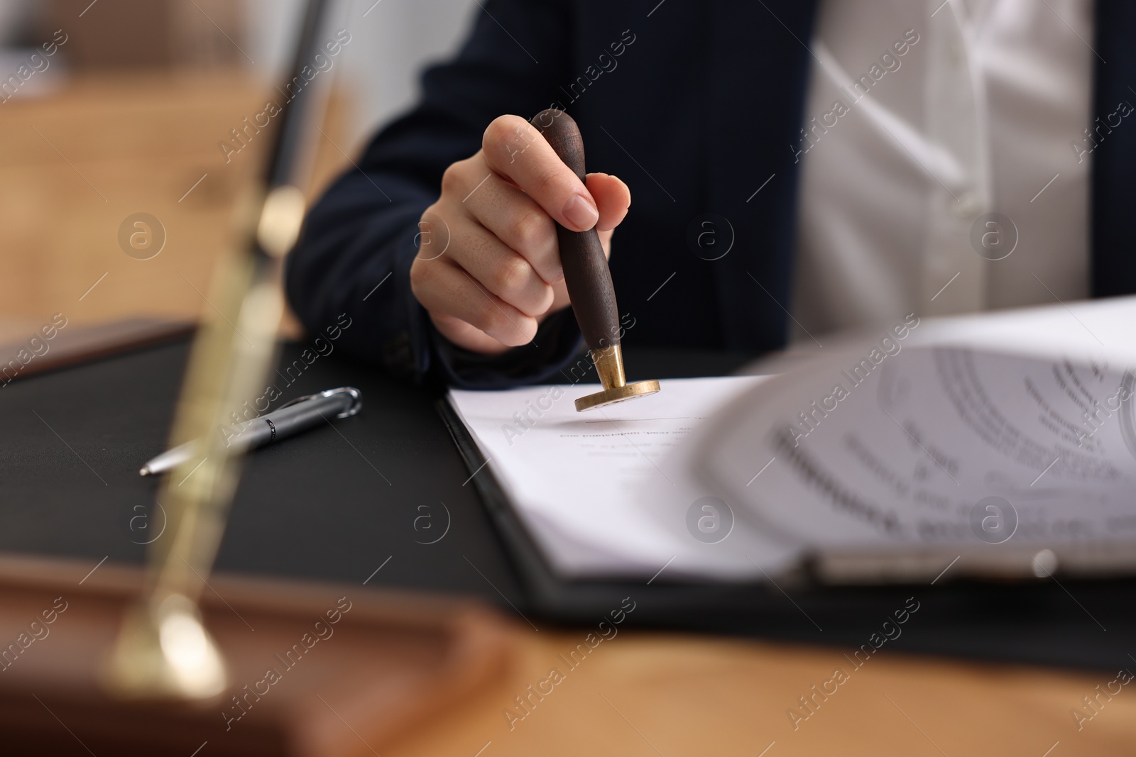 Photo of Notary sealing document at table in office, closeup