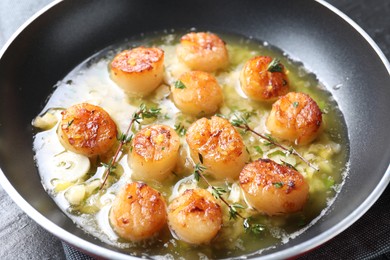 Delicious scallops with sauce in frying pan on table, closeup