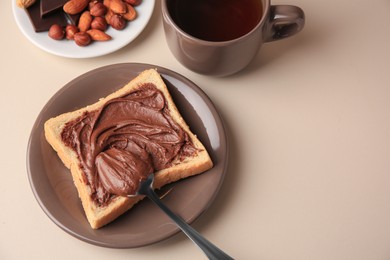 Photo of Tasty toast with chocolate paste and cup of tea served on light table, space for text