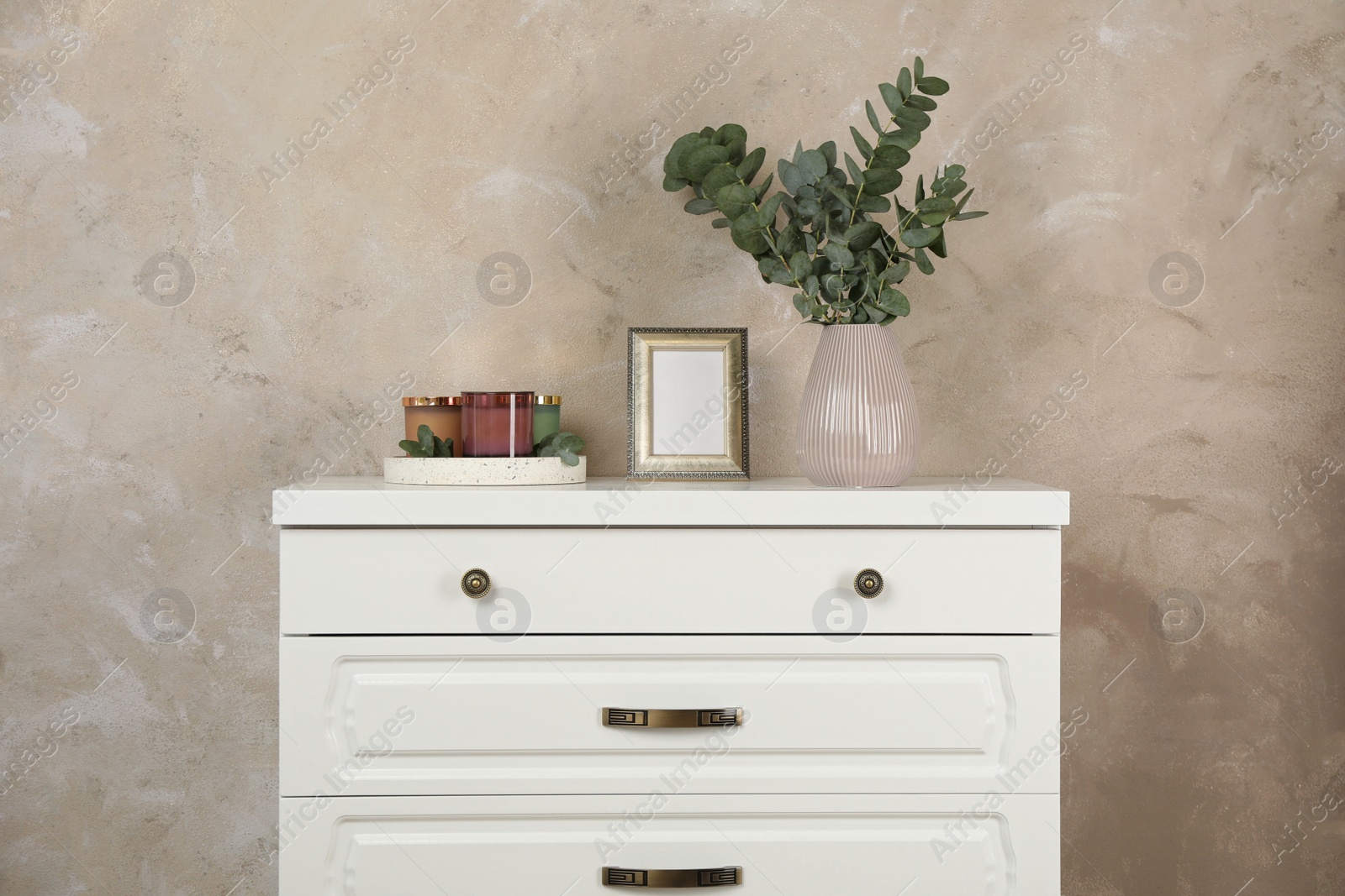 Photo of Modern chest of drawers with decor near beige wall