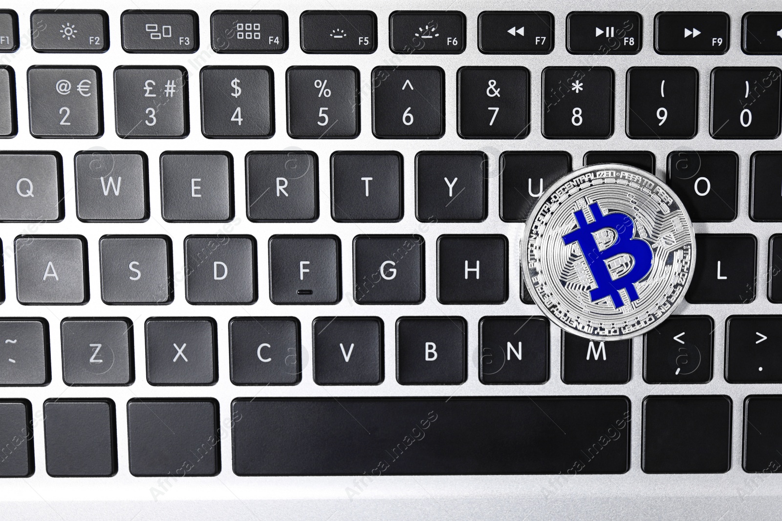 Photo of Silver bitcoin on computer keyboard, top view. Space for text