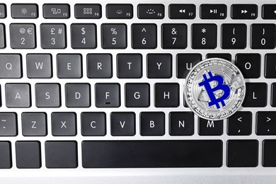 Silver bitcoin on computer keyboard, top view. Space for text