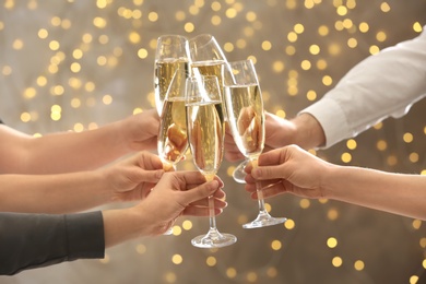 Photo of People clinking glasses with champagne against blurred lights, closeup. Bokeh effect