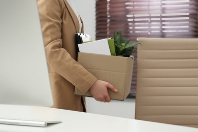 Photo of Upset dismissed woman carrying box with personal stuff in office, closeup