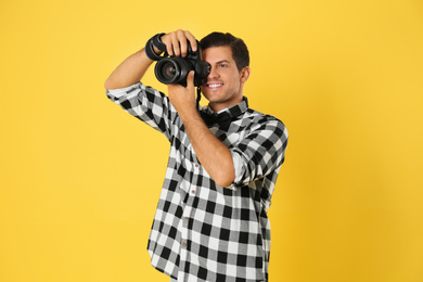 Photo of Professional photographer working on yellow background in studio