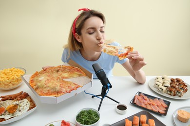 Photo of Food blogger eating in front of microphone at table against light background. Mukbang vlog
