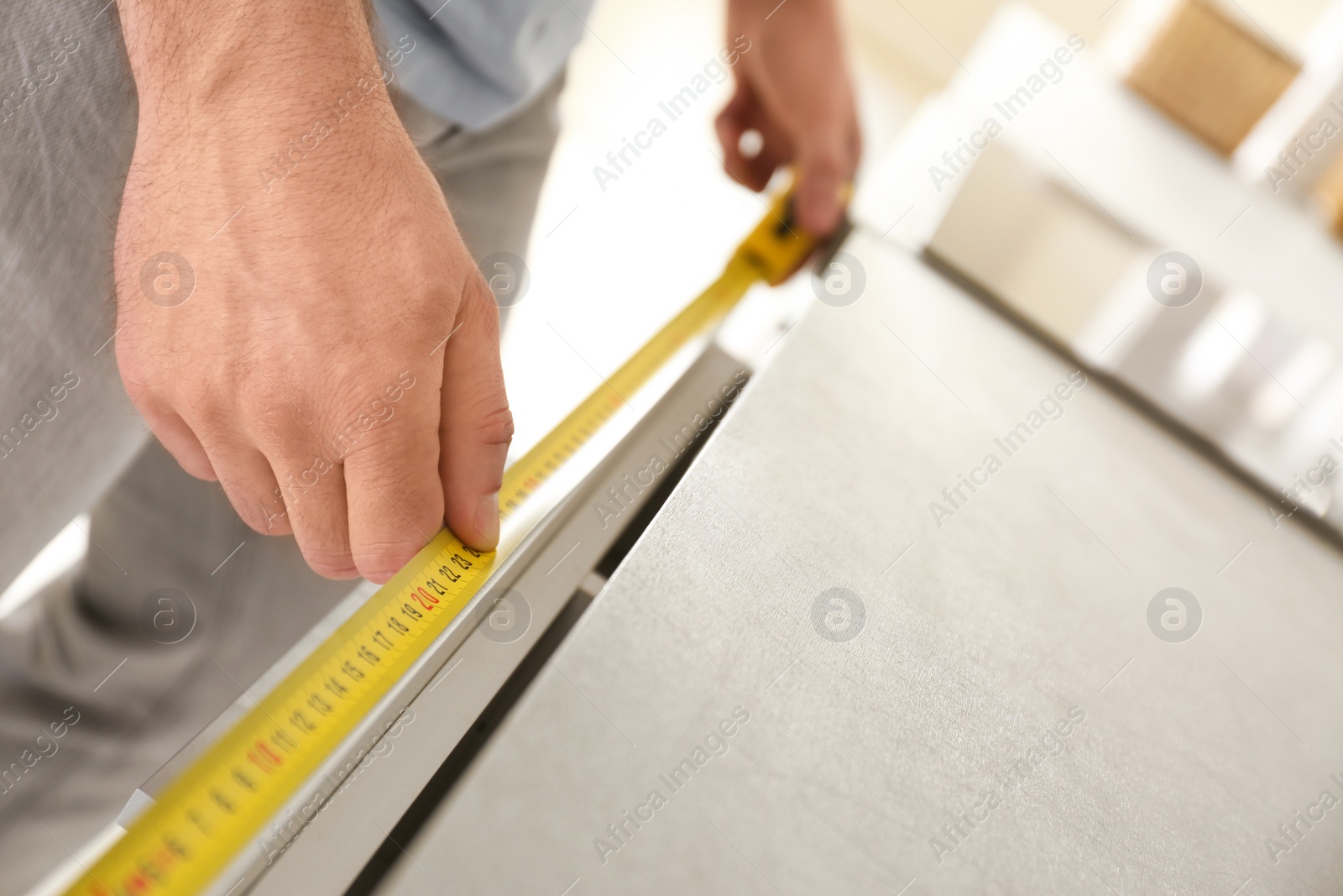 Photo of Man measuring kitchen furniture indoors, closeup. Construction tool