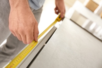 Man measuring kitchen furniture indoors, closeup. Construction tool