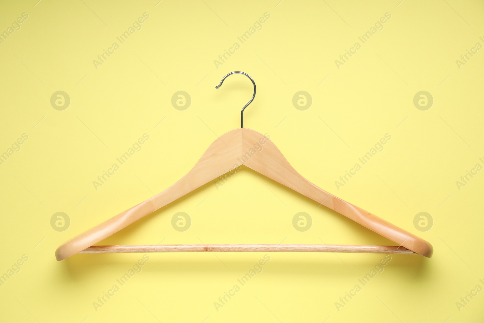 Photo of Empty wooden hanger on yellow background, top view